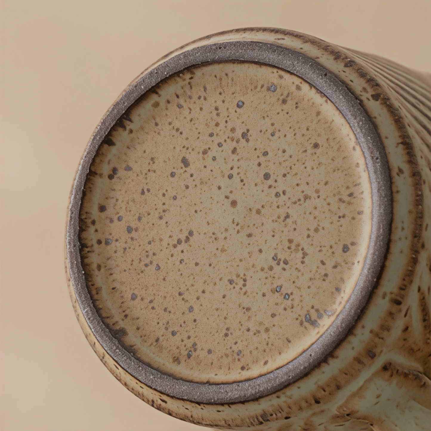 Close-up of handmade stoneware mug with spiral grooves and matte earthy glaze, ideal for coffee or tea lovers. Coarse handmade ceramic surface, smooth finish inside.