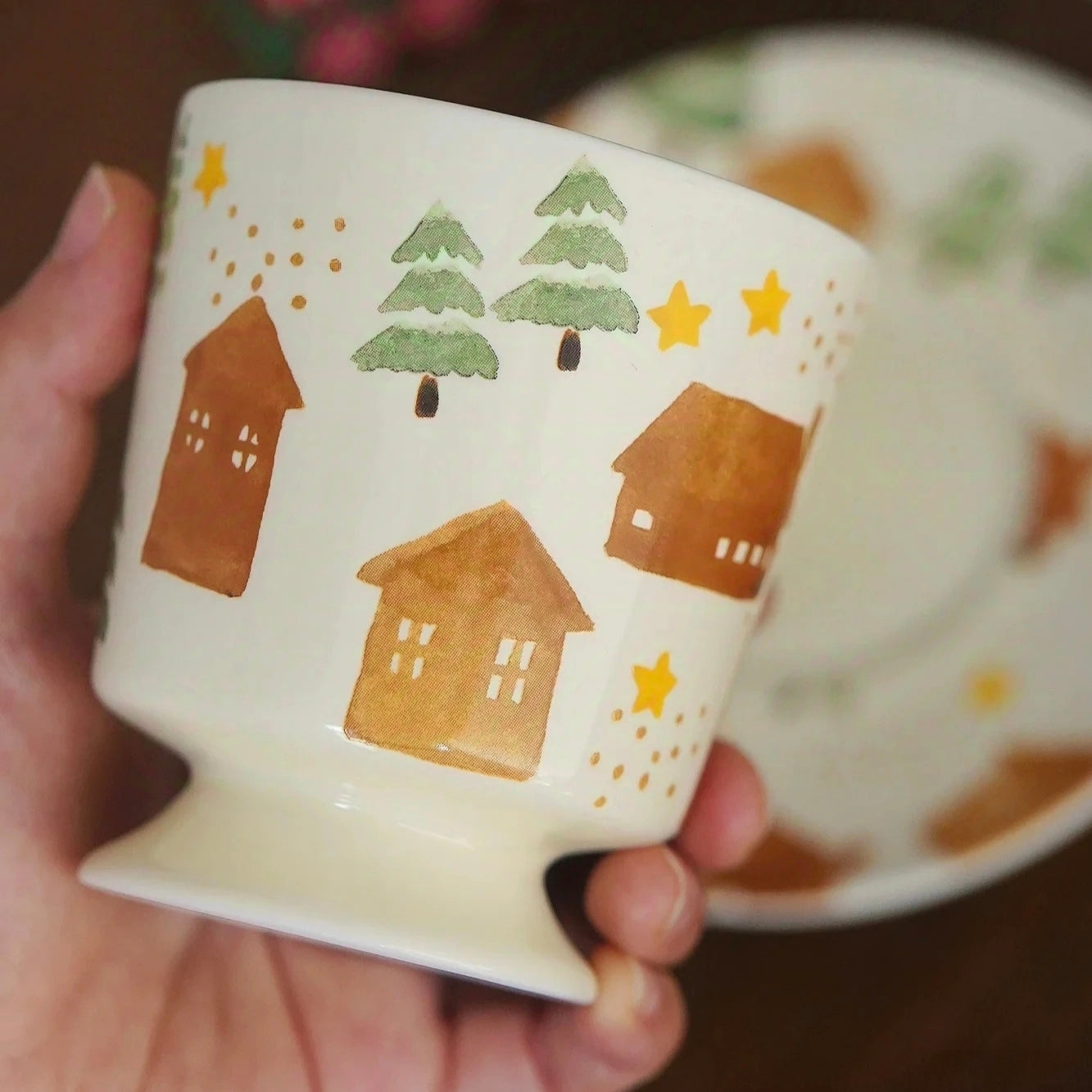 Artistic winter-themed coffee cup with matching saucer in soft pastel glaze, perfect for holiday drinks.