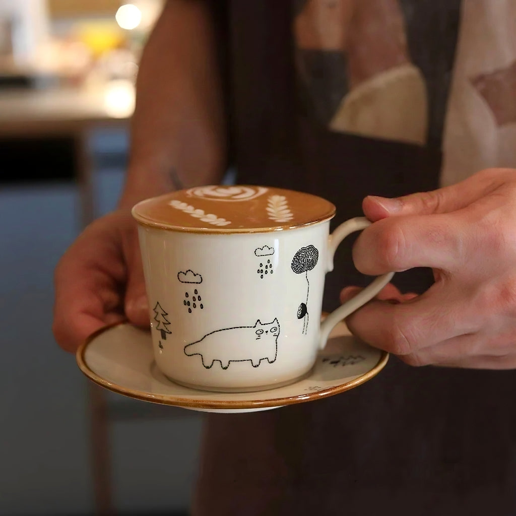 Cute hand-illustrated coffee cup with cat and rain theme, round handle design, microwave-safe and dishwasher-safe. Rustic artisan coffee mug suited for Zakka or adorable Scandinavian home style.