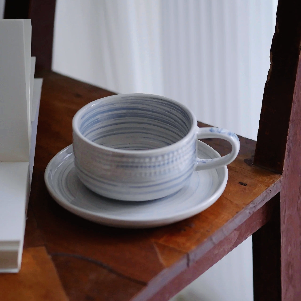 Handcrafted pottery cup with blue brush strokes and creamy glaze—perfect gift for coffee lovers.