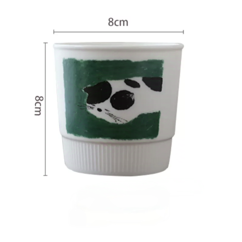 Whimsical handmade pottery mug showcasing a cat curled up for a nap. Soft Nordic colors and minimalist style make it a cozy and cute drinkware choice for any stylish kitchen or desk.