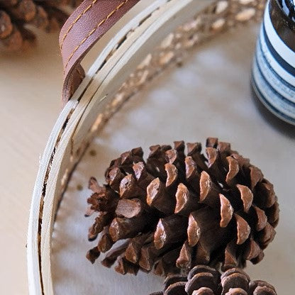 Detailed close-up of the intricate rattan weave on a round wicker storage tray with leather handles, highlighting its handmade craftsmanship.