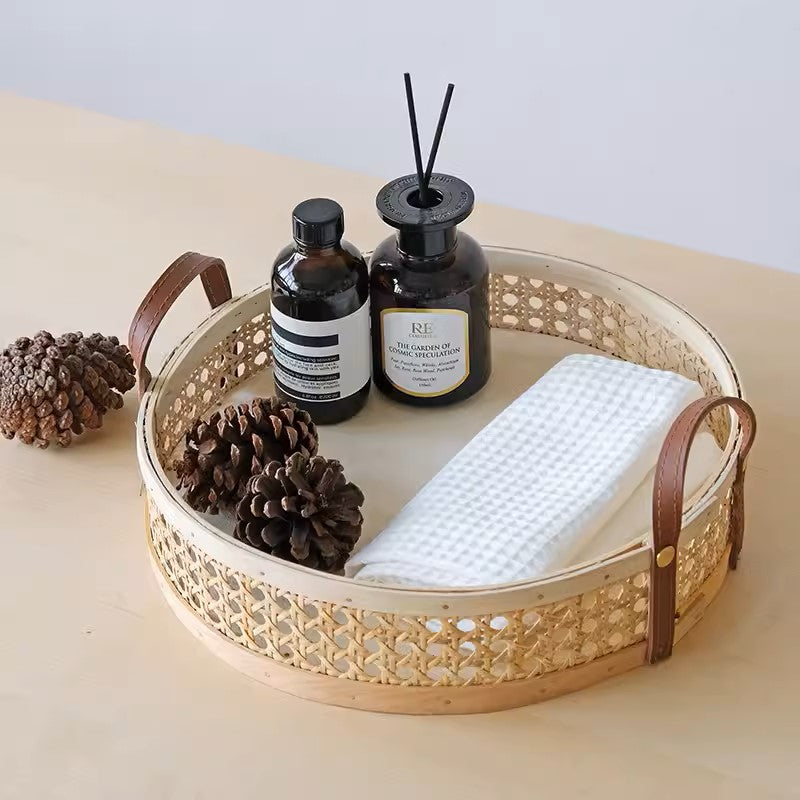 Handmade rattan storage tray in natural wood color, used in a hallway to hold incense and decorative candles, featuring leather handles for easy mobility and available in various sizes.