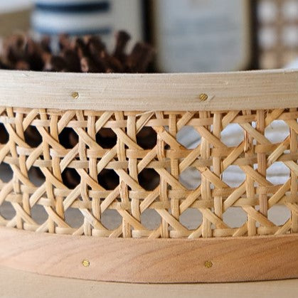 Detailed close-up of round rattan wicker storage tray, highlighting intricate handmade weaving and natural wood color.