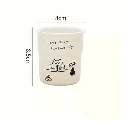 Cute ceramic coffee mug with playful hand-painted kitten reading a book, crafted in durable underglaze ceramic. Great for cozy moments and slow mornings with tea or coffee.