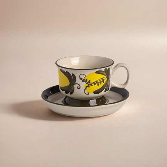 A Scandinavia ceramic tea cup with yellow and black botanical artwork.