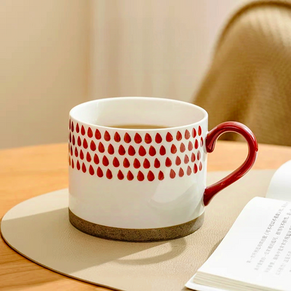 Artistic ceramic mug showcasing bold red motifs, blending traditional and modern design elements. Ideal for tea or coffee.