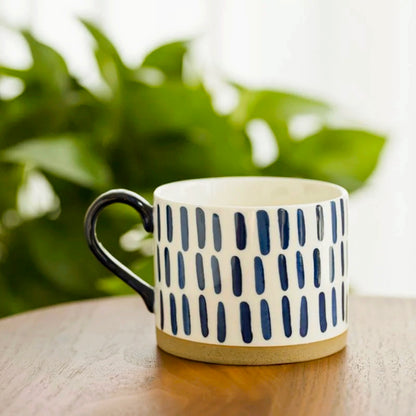 Hand painted ceramic mug featuring vertical line patterns, blending Nordic design with functionality.