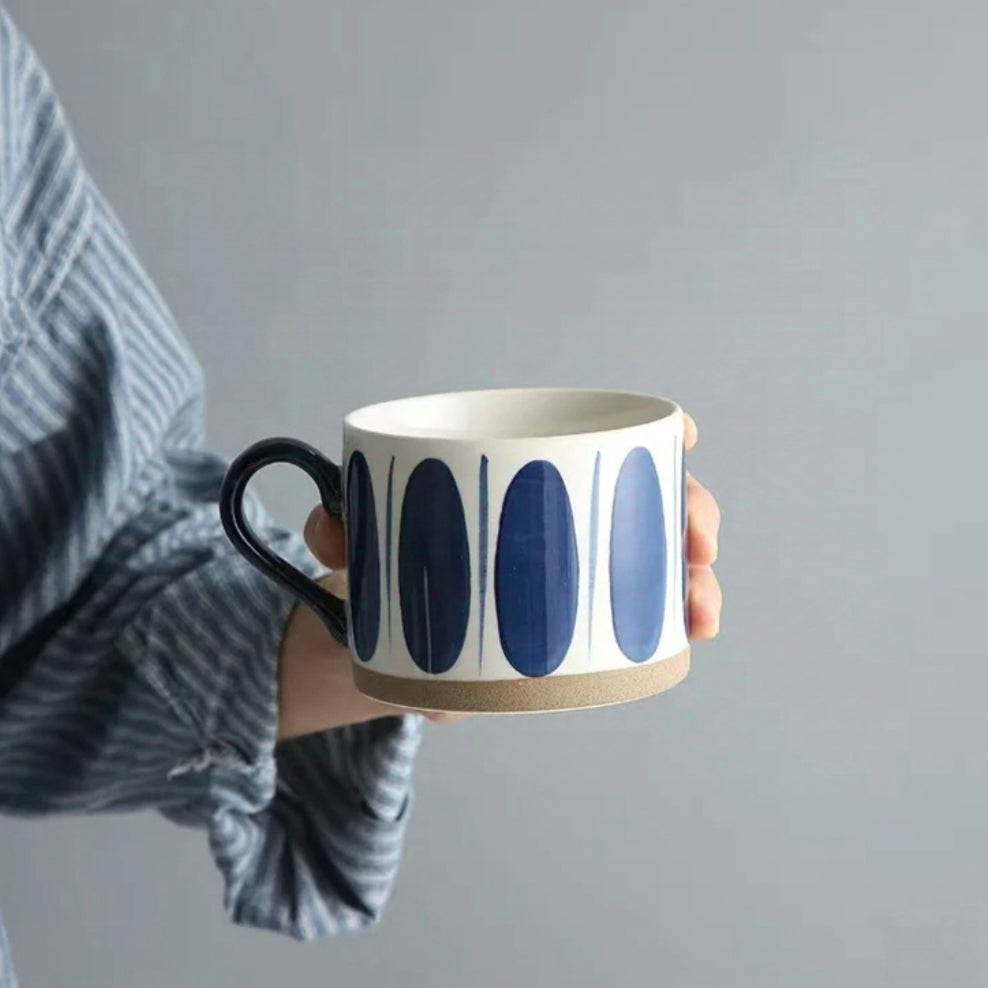 Cream-white and blue ceramic mug with delicate blue oval motifs, ideal for coffee and tea lovers.