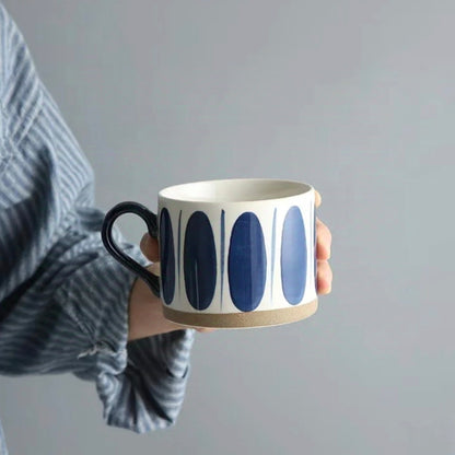 Cream-white and blue ceramic mug with delicate blue oval motifs, ideal for coffee and tea lovers.