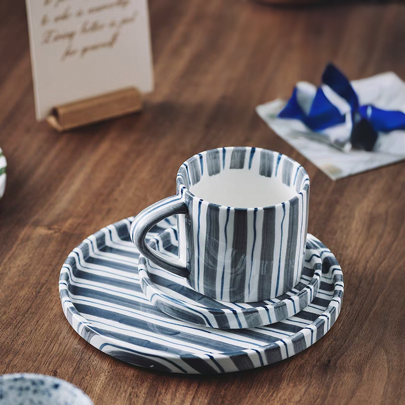 Elegant striped ceramic cup and plate set in cerulean blue, featuring hand-painted stripes on a neutral ceramic base, perfect for modern dining settings.