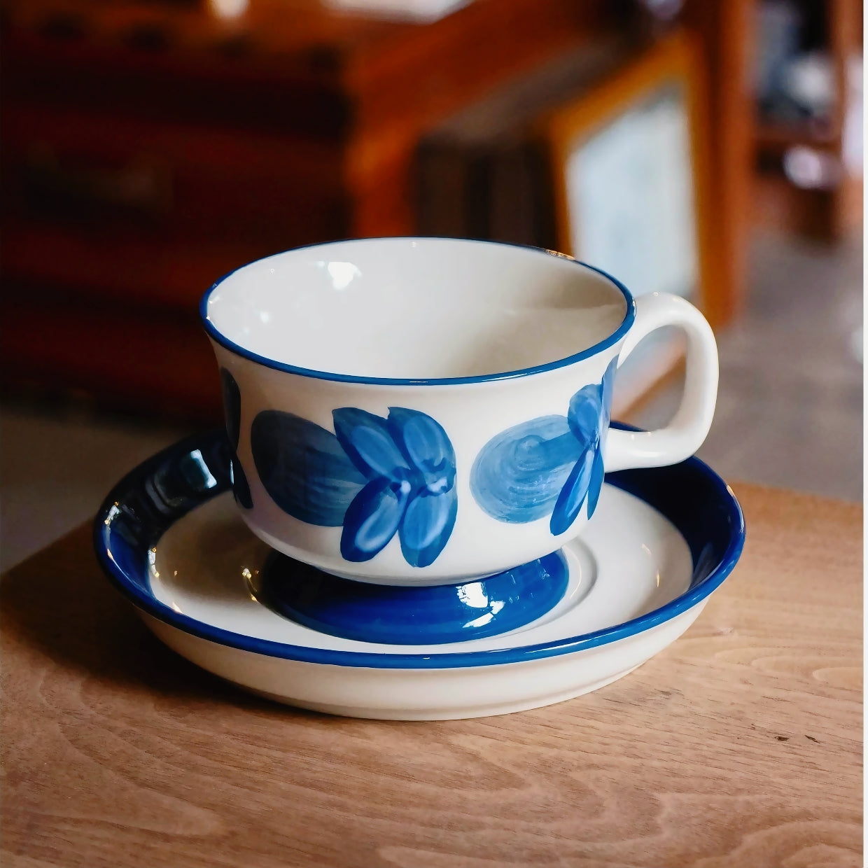 Ceramic coffee cup featuring hand-painted blue flowers with minimalist brushstroke style, perfect for daily use.