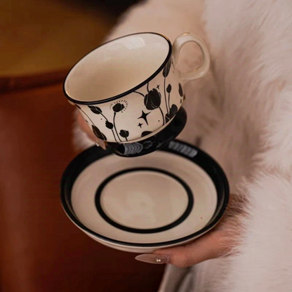 Ceramic coffee cup and pairing  saucer featuring black botanical silhouettes with star and sun motifs, perfect for minimalist decor.