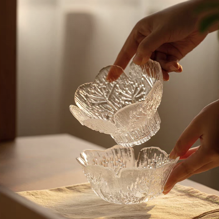 A high-footed glass bowl and a flat-bottom bowl with intricate floral embossing, designed for desserts and fruit in modern kitchens.