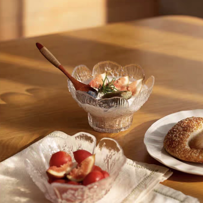 Pedestal-style glass dessert bowl holding yogurt with toppings, highlighting its clear material and embossed floral pattern.