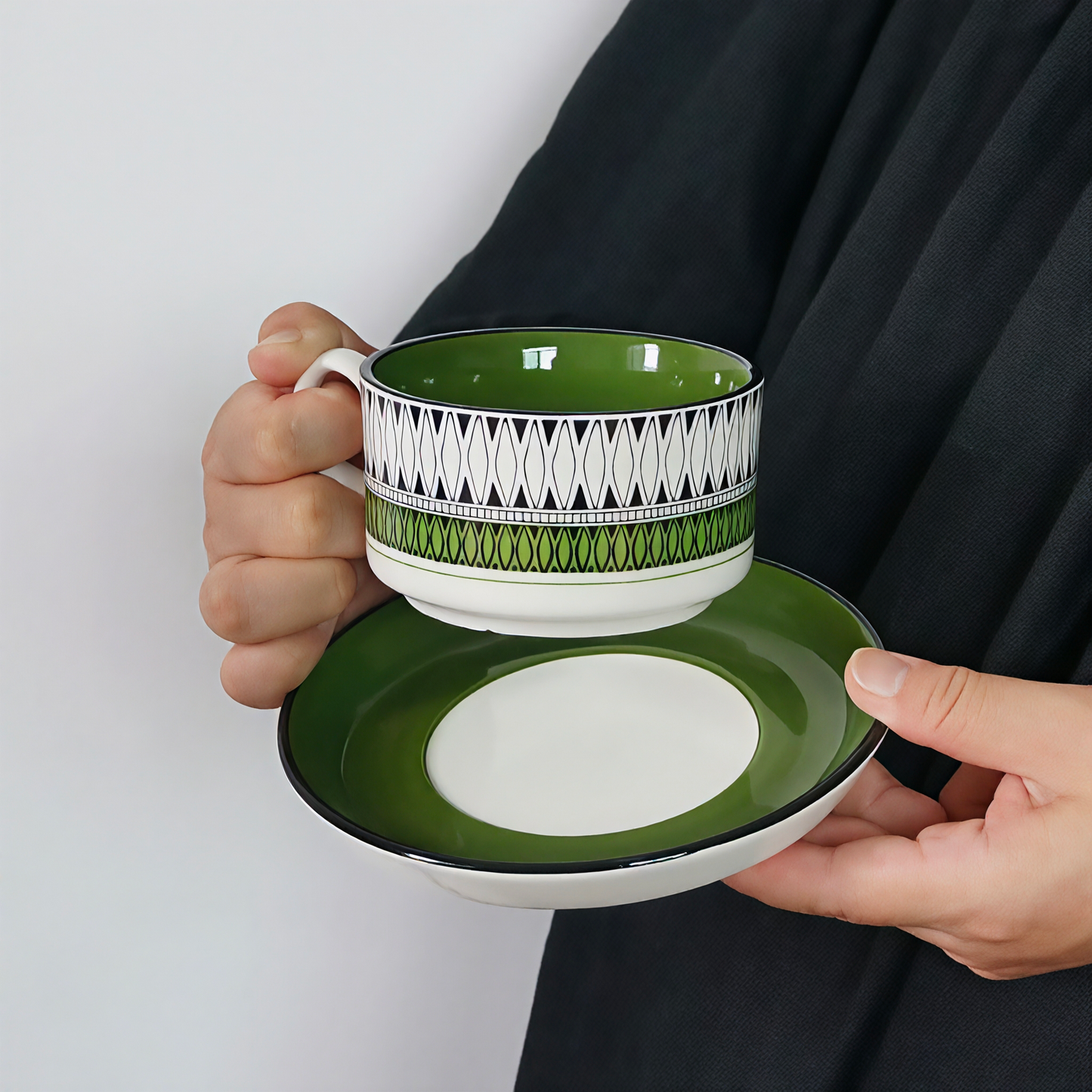 A boho-style ceramic mug with bold green patterns and a saucer for coffee or tea.