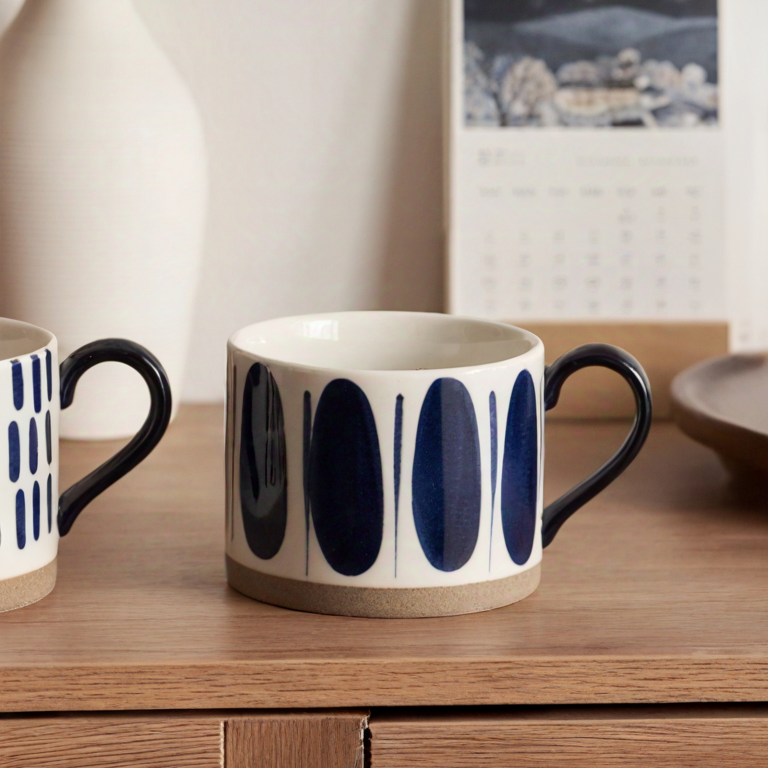 Elegant ceramic mug with hand-painted blue oval and lines, perfect for minimalist homes.