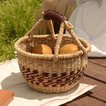 Hand-woven seaweed basket filled with fruits during an outdoor picnic, combining nature-inspired aesthetics and functionality.