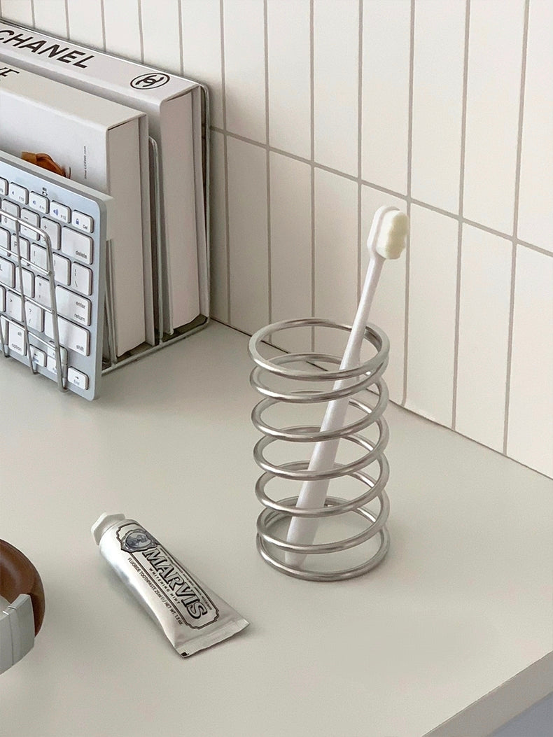 Metal-made spiral brush holder, combining durability and aesthetic appeal, ideal for organizing various bathroom essentials.