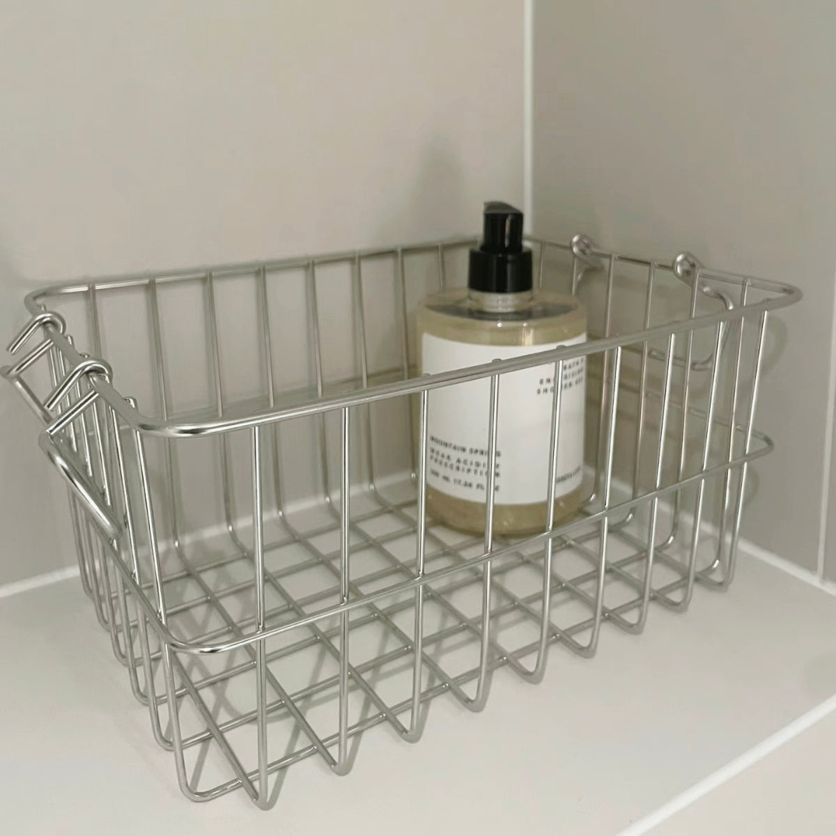 High-quality stainless steel storage basket for bathroom use, perfect for storing bottles, jars, and cosmetics. Features double handles and a sleek design.