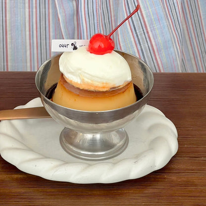 Sleek stainless steel dessert dish used for serving pudding in a café, demonstrating its aesthetic appeal and versatile use in a minimalist setting.