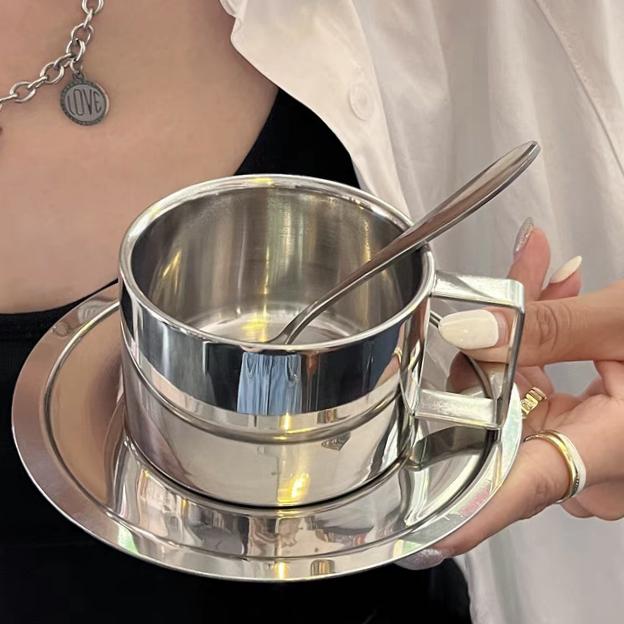 Stylish stainless steel coffee cup with tray and spoon, featuring a modern and industrial design, perfect for café and kitchen use.