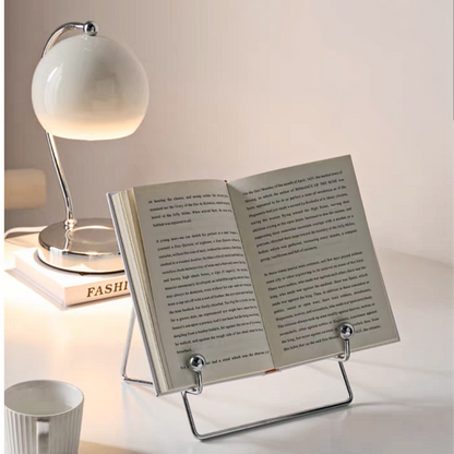 Stylish stainless steel book stand with a sleek, minimalist design, displayed with a book.