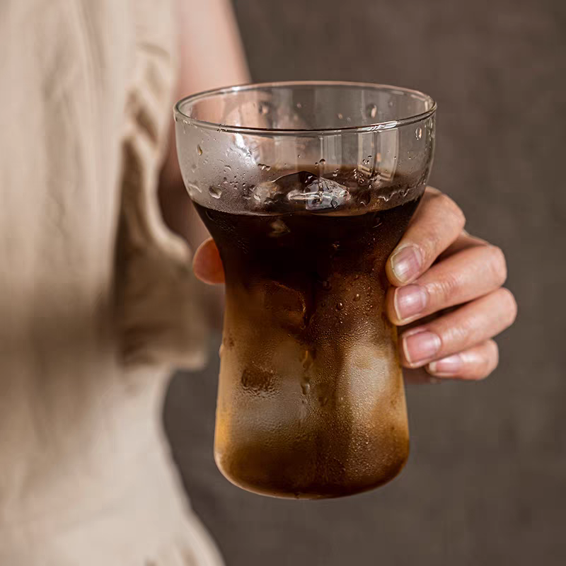 Sleek ergonomic glass cup showcasing iced coffee, blending style and functionality.