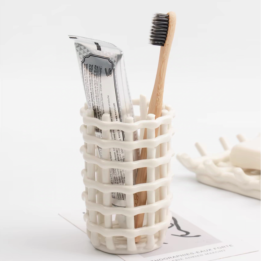 This ceramic holder with a woven design neatly organizes toothbrushes on a bathroom countertop, ideal for minimalist and Scandinavian decor.