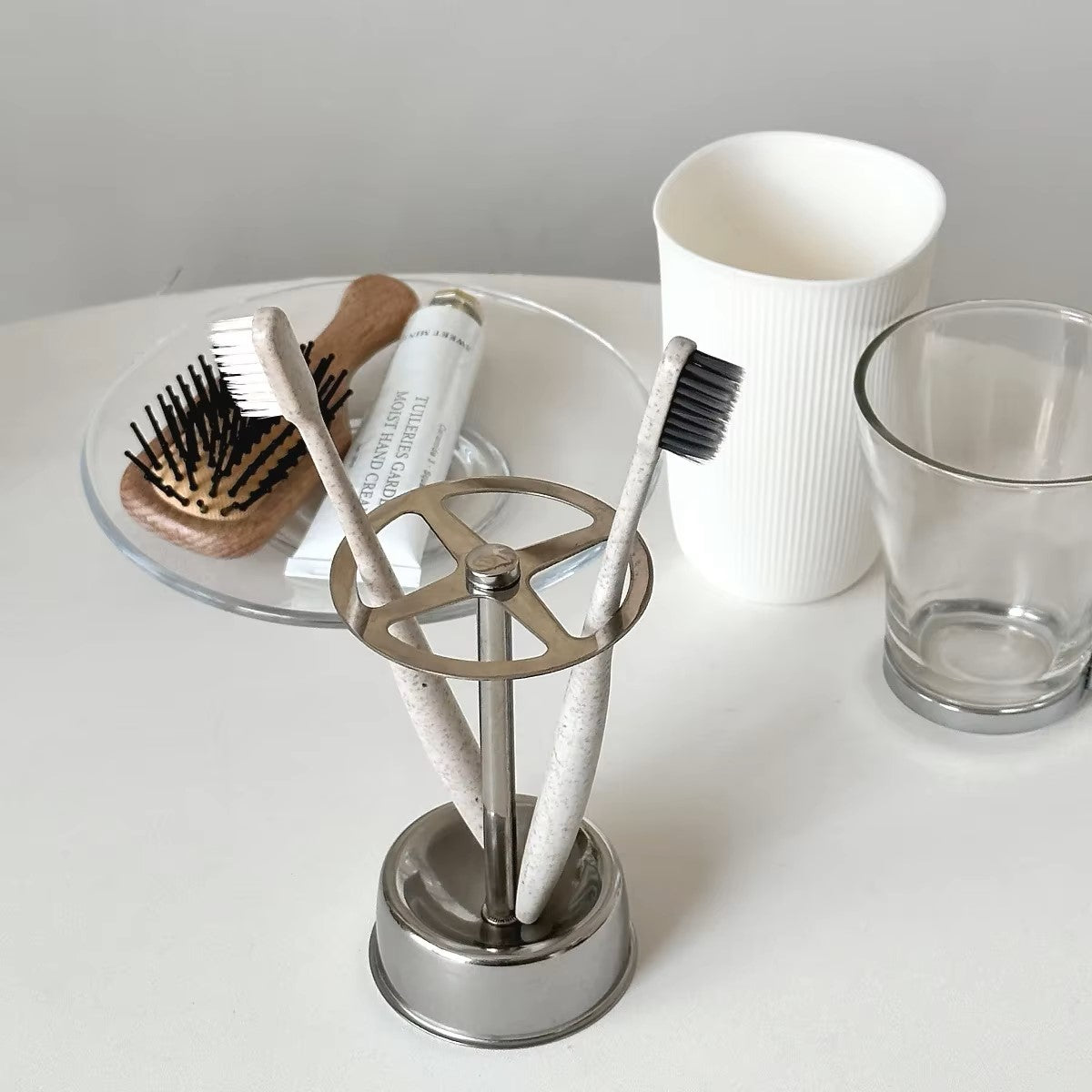 Minimalist stainless steel brush holder with four grids, elegantly storing toothbrushes on a vanity countertop.