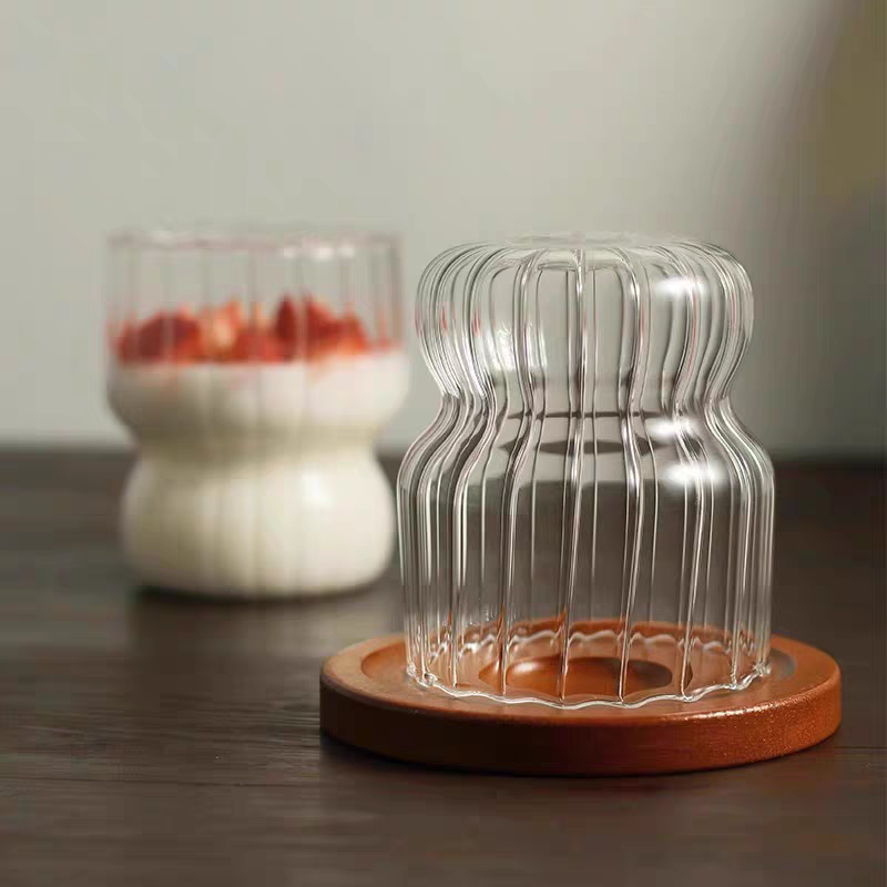 A clear ribbed glass cup with a smooth base and elegant wave texture for modern, minimalist, Nordic homes. Durable and dishwasher save.