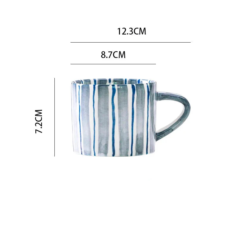 Modern ceramic cup with hand-painted cerulean blue stripes, designed in a minimalist Scandinavian style. The ergonomic handle adds comfort, perfect for coffee or tea in a Nordic-inspired setting.