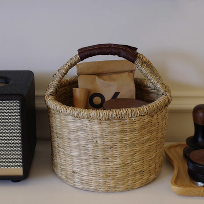 Hand-woven natural seaweed basket filled with various coffee, snacks and supplies, demonstrating its functional and decorative use in dinning room.