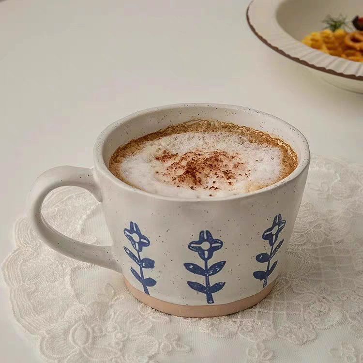 Handcrafted ceramic cups in neutral colors with a subtle, minimalist Japandi-inspired blue floral pattern, perfect for tea or coffee. Durable and long-lasting.