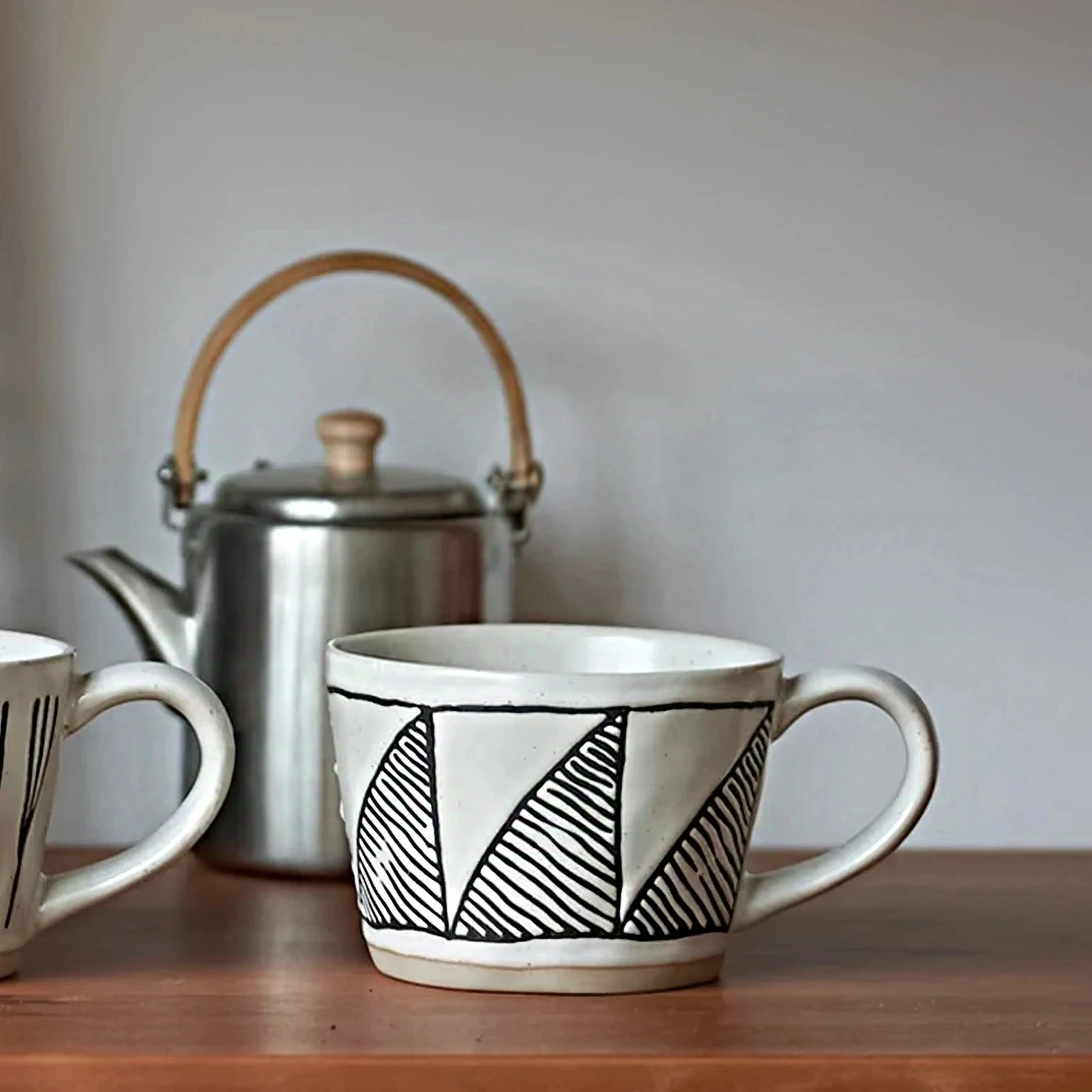 Elegant ceramic mug with hand-painted black triangles, perfect for minimalist, Nordic, rustic homes. Microwave and dishwasher safe.