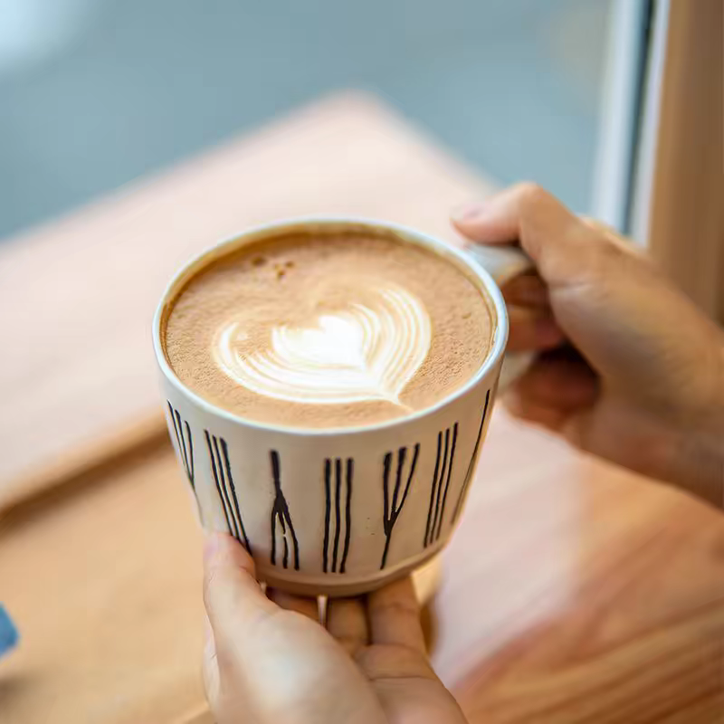 Artisan ceramic cup featuring bold black abstract patterns, 350 ml/ 11.8 oz, filled with latte. Ideal for minimalist and Japandi interiors. 