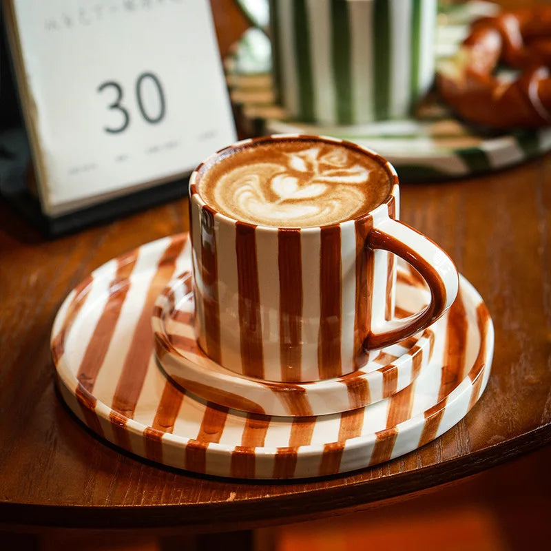 Hand-painted ceramic cup and matching plates in burnt orange stripes, showcasing minimalist Nordic design and modern functionality for drinks and desserts.