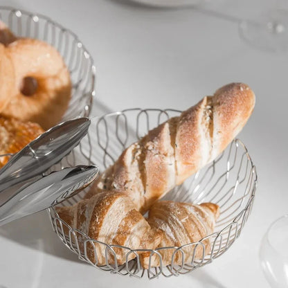 A loaf of bread placed in a sleek, polished stainless steel basket, ideal for serving bread in minimalist kitchens.