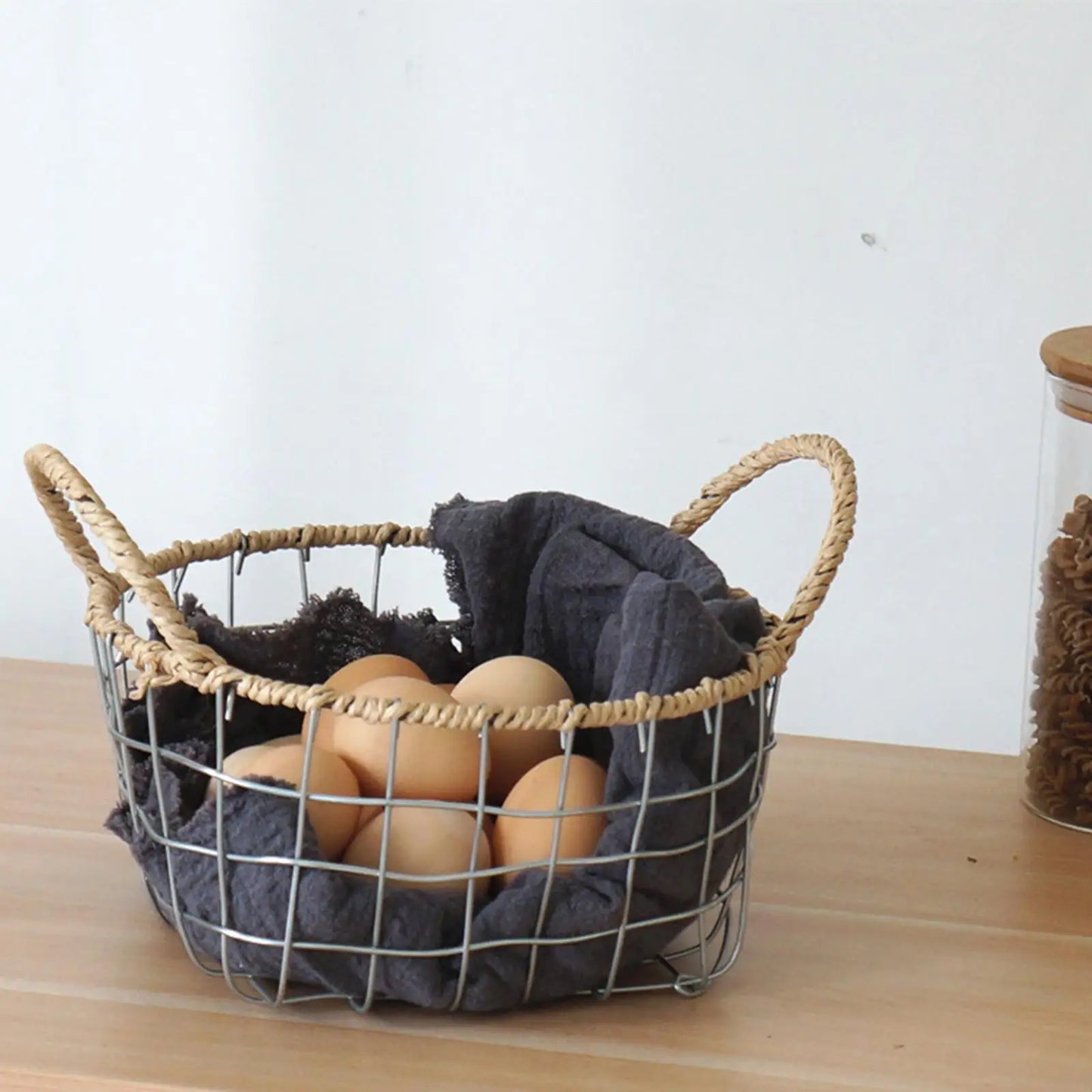 Round woven metal wire basket filled with eggs, showcasing its versatile and decorative features in a warm minimalism setting.