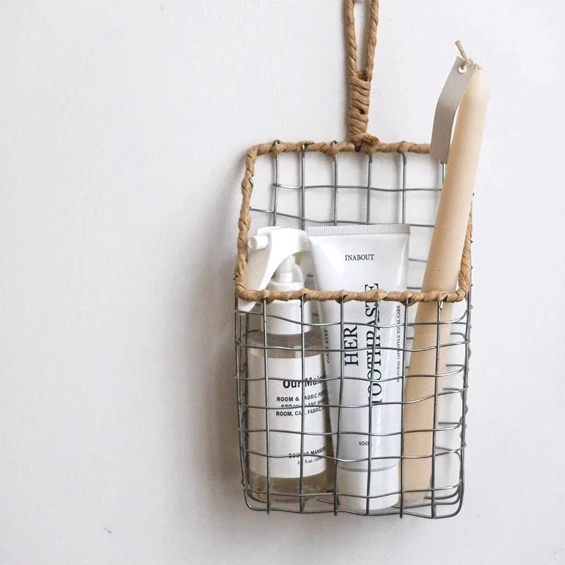 Handwoven metal wire basket, hanging on a hook, storing small kitchen tools and cleaning supplies, perfect for natural-inspired decor.