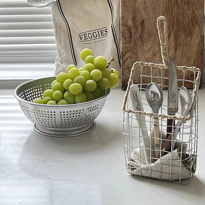 Hanging metal wire storage basket in the kitchen, filled with fresh fruits and vegetables, highlighting eco-friendly design.