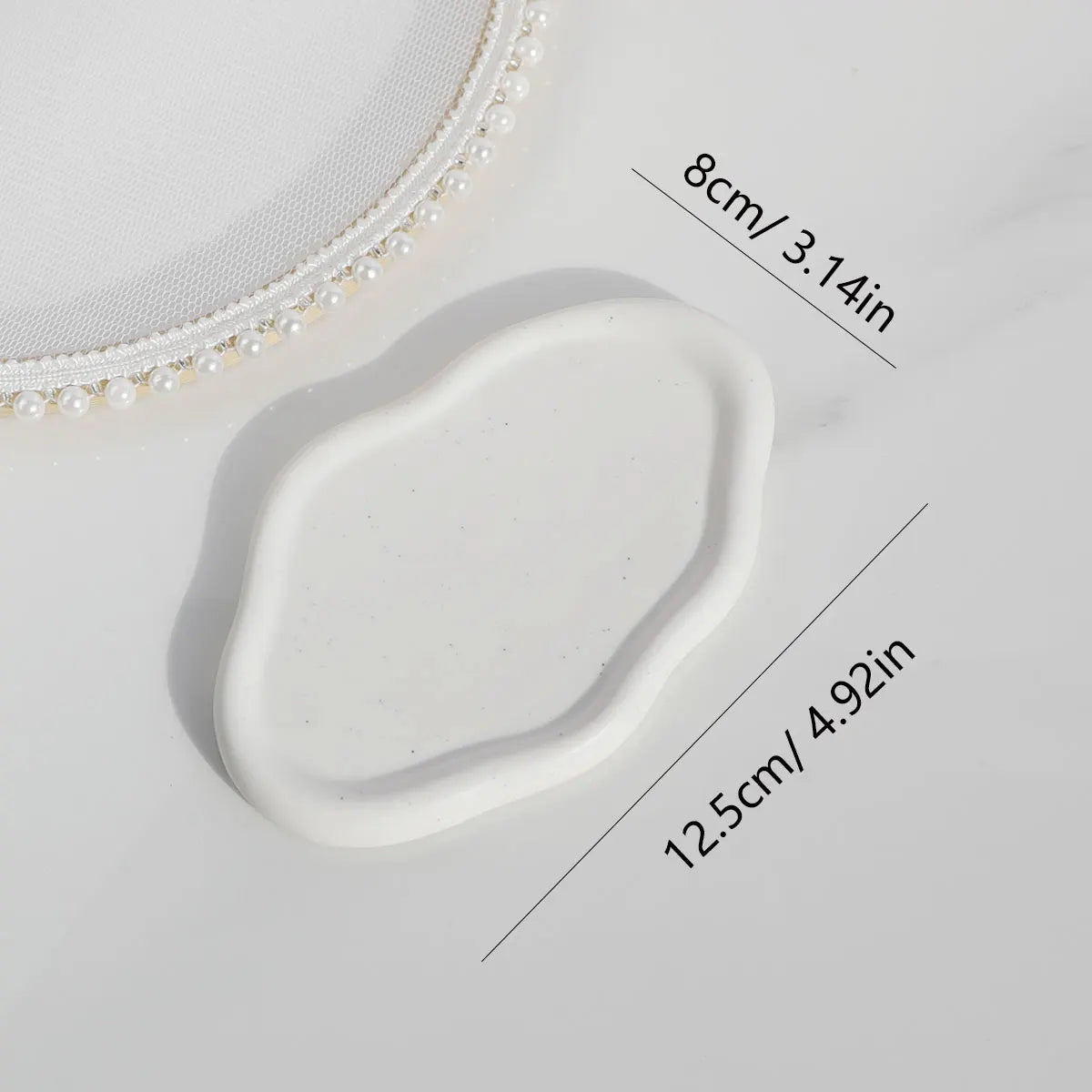 White oval ceramic tray placed on a table, emphasizing its elegant shape and convenient size, ideal for jewellery and key storage in contemporary spaces.