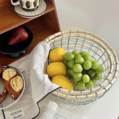 Round woven metal wire basket with assorted fruits, highlighting its eco-friendly rattan and metal construction.