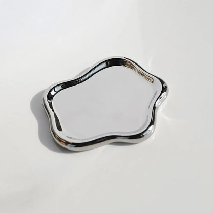 Silvery cloud-shaped metal tray, neatly organizing rings, necklaces, and bracelets, highlighting its stylish design and practical use.