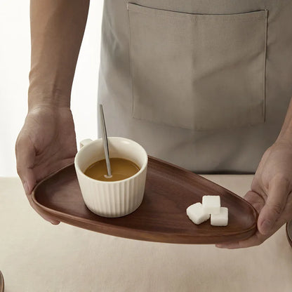 Irregular oval-shaped solid wood tray used for serving coffee, showcasing the elegant walnut wood finish and handmade quality.