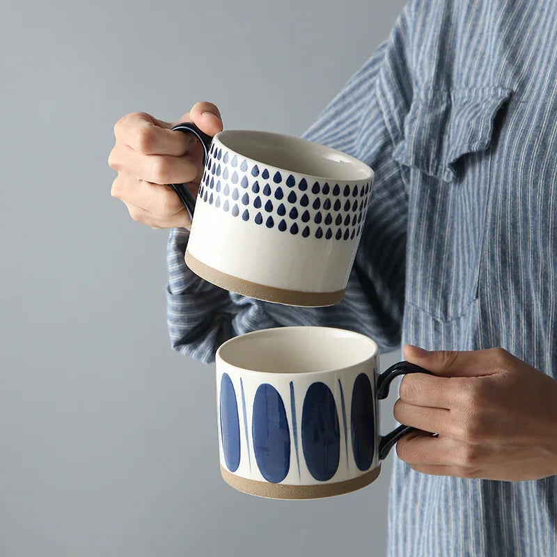 Collection of four cream-white ceramic cups with unique blue patterns, ideal for coffee, tea, and milk in stylish, minimalist settings.