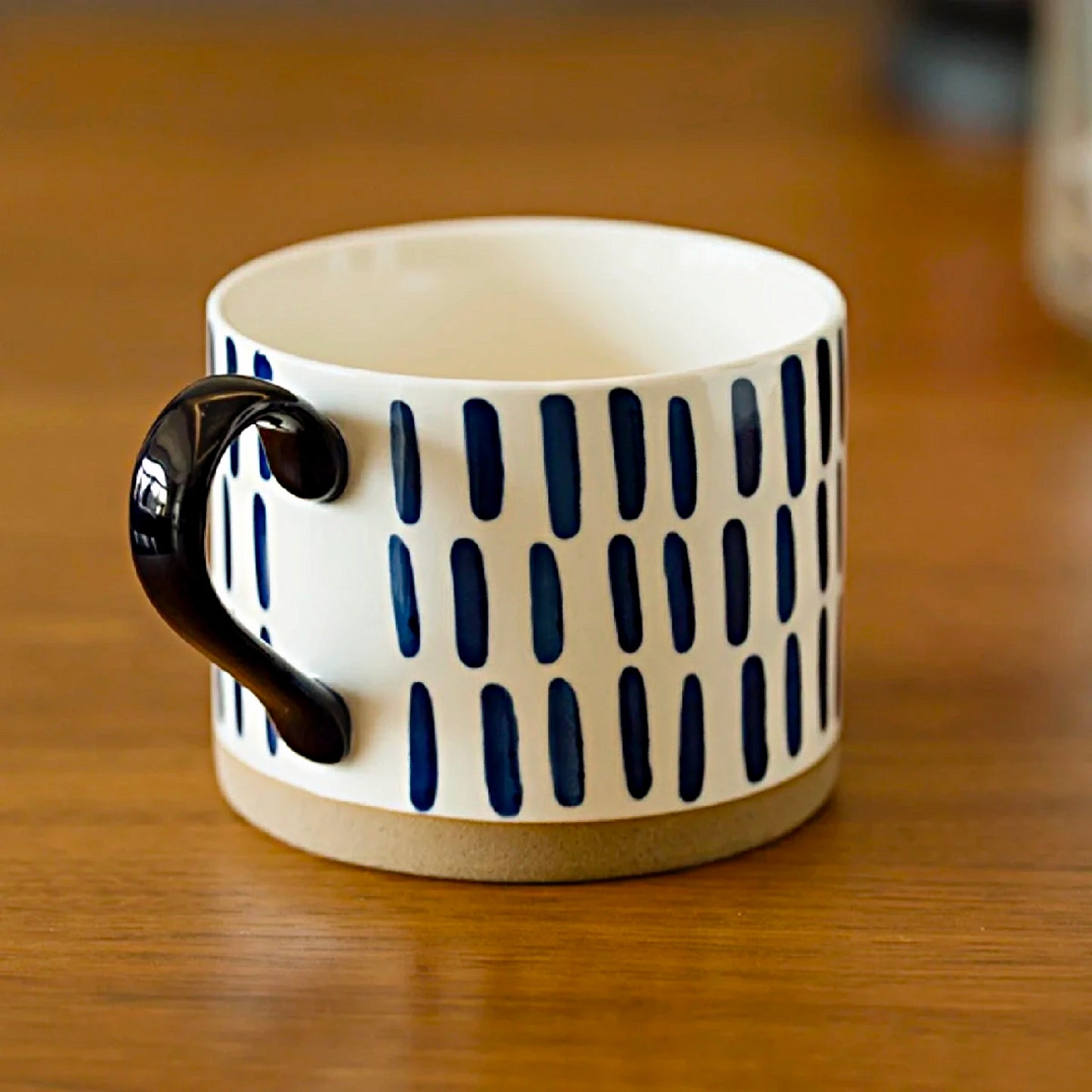 Cream-white and blue ceramic cups with unique blue vertical lines, ideal for coffee, tea, and milk in stylish, minimalist settings.