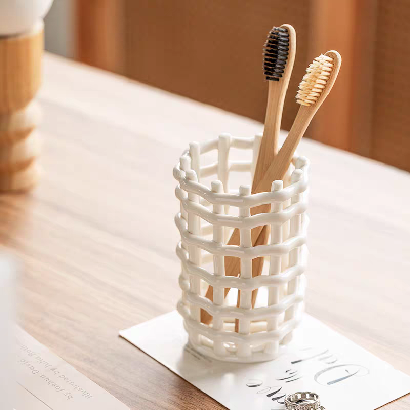 A ceramic toothbrush holder with a hollow bottom for easy drainage, beautifully designed for simplicity and functionality on the bathroom countertop.