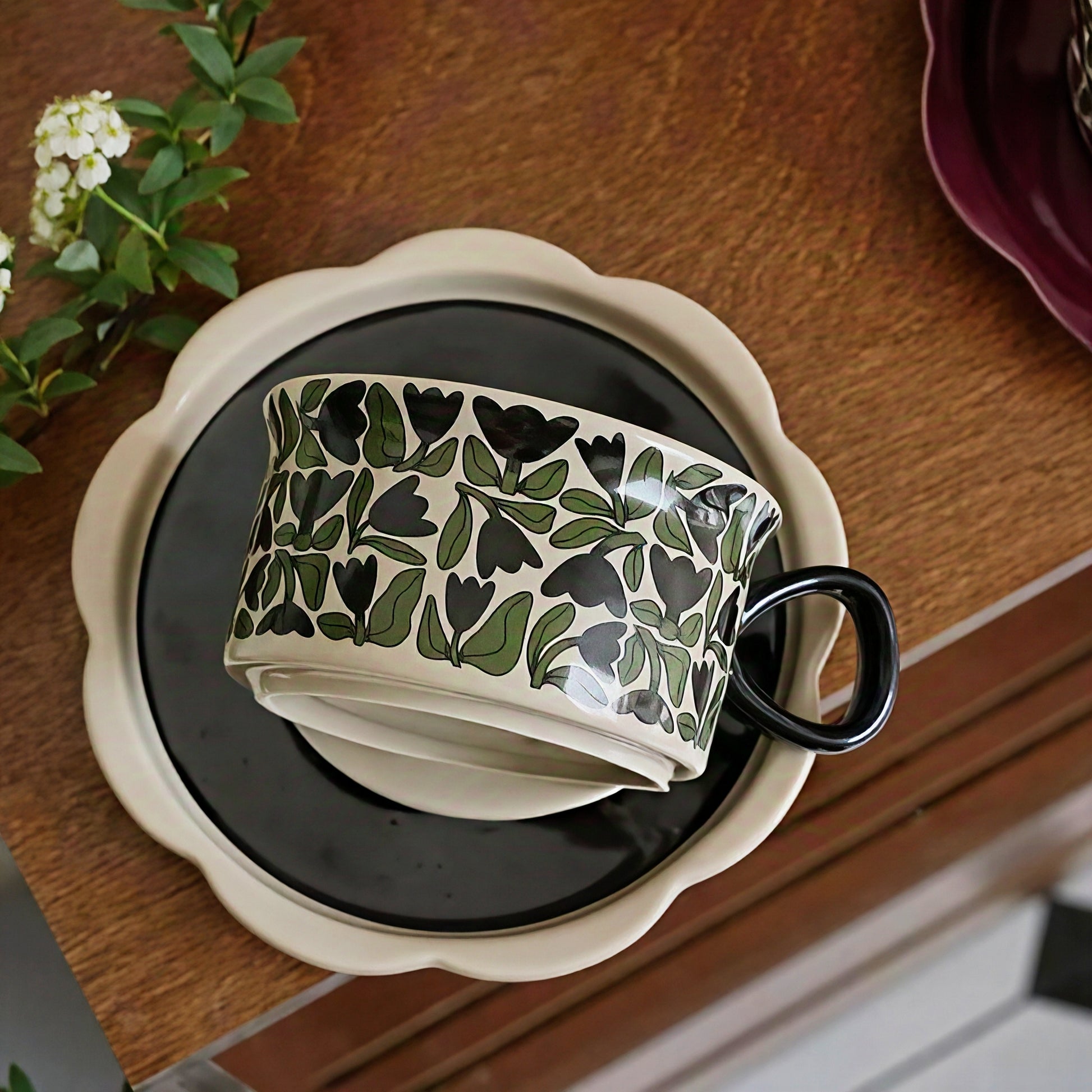 Minimalist coffee mug and saucer featuring Nordic black and green floral motif, perfect for cozy home interiors. Microwave, dishwasher and oven safe.