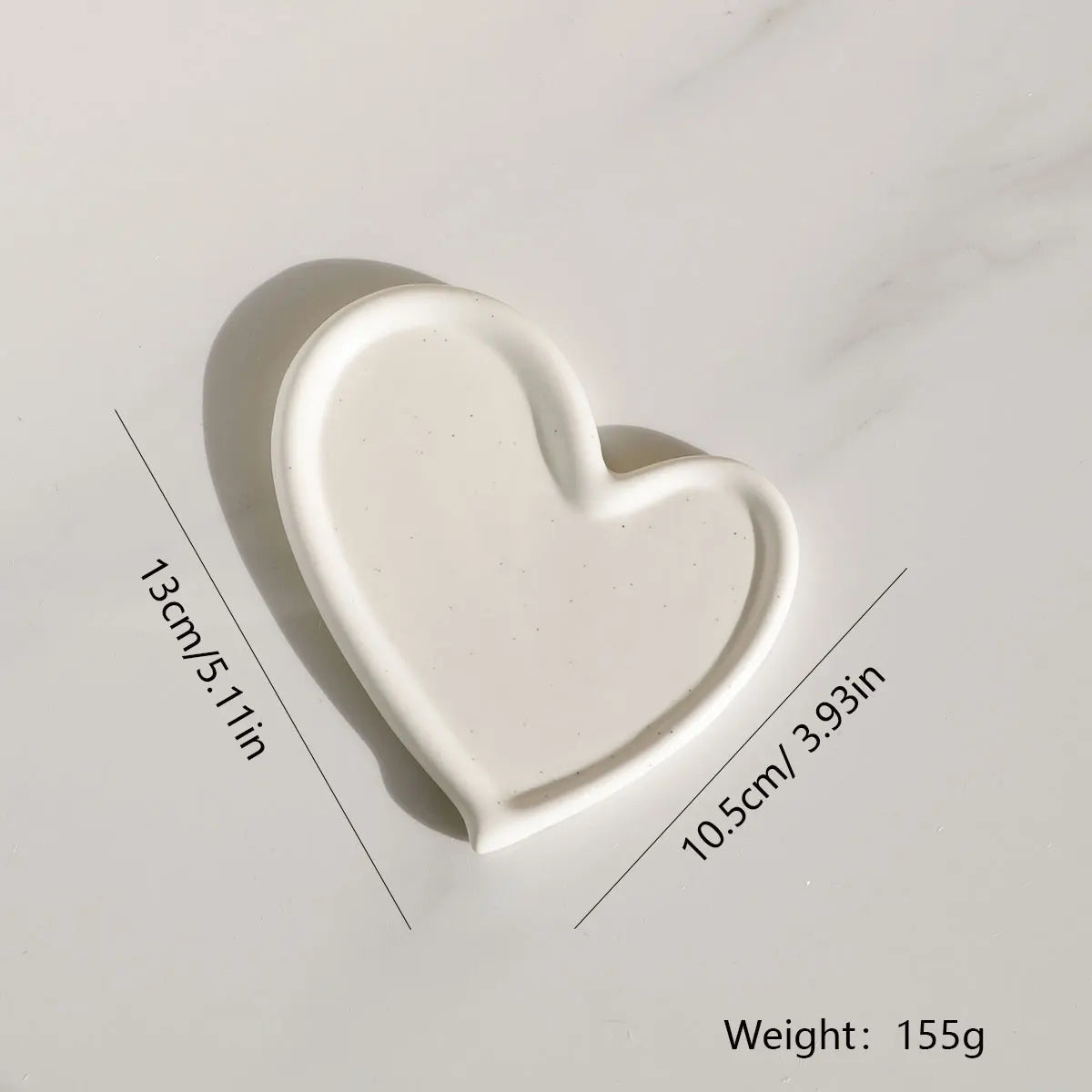 White heart-shaped ceramic tray, highlighting its unique design and suitable size for organizing jewellery and keys.